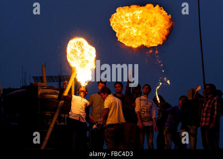 Dhaka, Dhaka, Bangladesh. 14. Januar 2016. 14. Januar 2016 - Dhaka, Bangladesch '' "alte Dhaka Gemeinschaft Menschen genießen posh Sankranti mit verschiedenen Aktivitäten, wie ein Mann Feuer am Abend am alten Dhaka bläst. Paush Shankranti "ist der letzte Tag des Bengali Monats Paush. Dieses traditionelle fest wird vor Ort bekannt als "˜Shakhrine". Schon flogen viele Kites am Himmel dahin. Verschiedene Farben und Größen. Die meisten von den Dächern dieser alten Gebäude waren besetzt mit Youngs (meistens) und einigen älteren. Bildnachweis: ZUMA Press, Inc./Alamy Live-Nachrichten Stockfoto