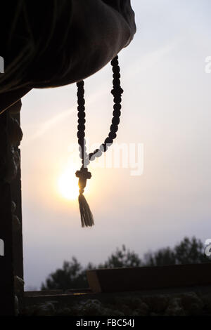 Silhouette des Gebets Hände halten christlichen Rosenkranz mit Kreuz gegen die Sonne am Himmel Stockfoto