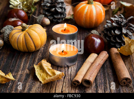 Herbst-Dekoration mit Kürbissen, Blätter, Kerzen, Zimtstangen, Kastanien und Eicheln Stockfoto