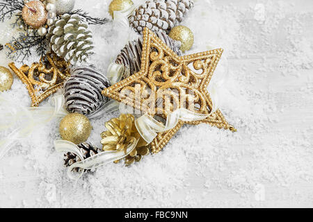 Golden glänzende Weihnachtsschmuck mit Band im Schnee Stockfoto