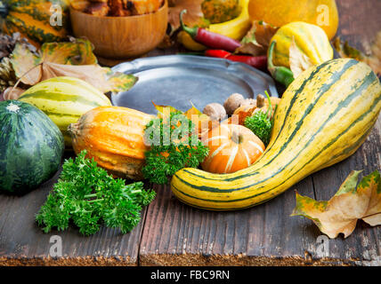 Herbstliche Dekorationen mit Kürbissen, getrocknete Blätter, Kastanien und Eicheln im hölzernen Hintergrund Stockfoto