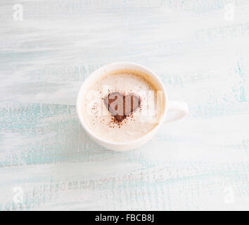 Latte-Kaffeetasse mit Kakao Herzform auf hölzernen Hintergrund Stockfoto