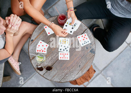 Draufsicht der drei jungen Freunde Spielkarten im Café. Die Jugendlichen spielen Kartenspiel im Coffee Shop. Stockfoto