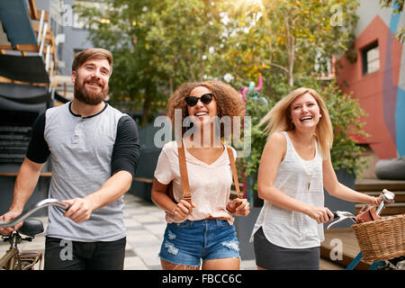 Schuss von Freunden mit ihren Fahrrädern zusammen im Freien. Gemischtrassig junger Mann und Frauen, die Spaß am Stadtstraße. Stockfoto