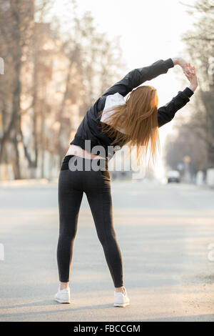 Läufer-Mädchen tun Aufwärmübungen für Wirbelsäule vor morgen Joggen auf der Straße, stretching, laufen zurück v vorbereiten Stockfoto