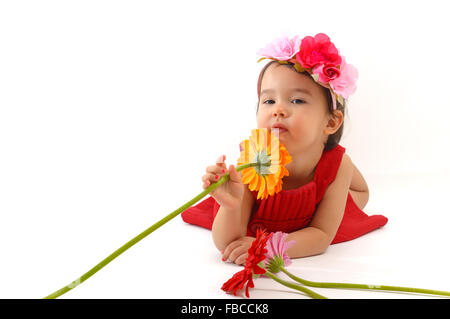 kleines Mädchen im roten Kleid eine Gerbera Blume riechen Stockfoto