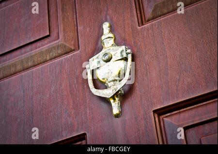 Eine antike Metall Klopfer auf eine Holztür, die Klopfer ist durch Feuchtigkeit stark beschädigt. Stockfoto