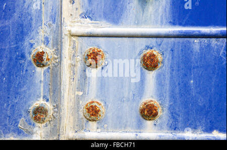 Teil einer verwitterten blauen Metallfläche mit rostigen Schrauben Stockfoto