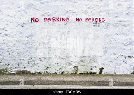 Kein Parkplatz Warnung besprüht mit roter Farbe auf einem weißen Stein Wand Stockfoto