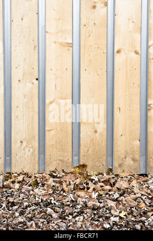 Teil der Wand von einem hölzernen Eco Gebäude mit Laub auf dem Boden Stockfoto