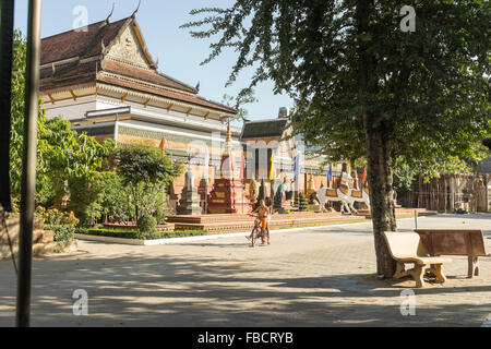 Kinder fahren mit dem Fahrrad durch die Anlage von Wat Preah Prom Rath in Siem Reap, Kambodscha. Stockfoto