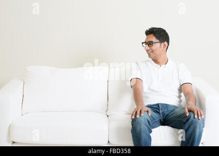 Junge Alleinstehende Inder auf Sofa allein und suchen auf Seite textfreiraum sitzen. Lebensstil asiatischer Mann zu Hause. Gut aussehend männlichen Modell. Stockfoto