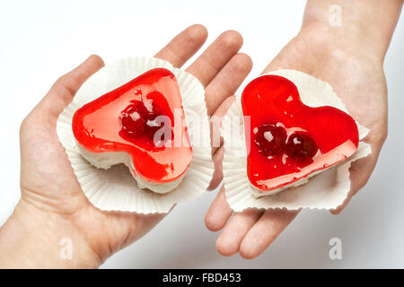 Gelee, herzförmigen Kuchen in Händen der Liebenden auf weißem Hintergrund Stockfoto