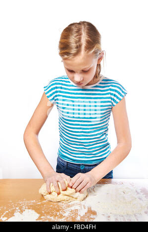 Mädchen knetet den Teig für den Kuchen auf dem Küchentisch isoliert Stockfoto