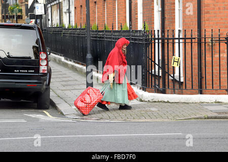 London, England, Vereinigtes Königreich. Frau mit rotem Schal und mit Gepäck zu Fuß in Kensington Stockfoto