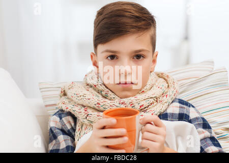 krank junge mit Grippe in Schal Teetrinken zu Hause Stockfoto