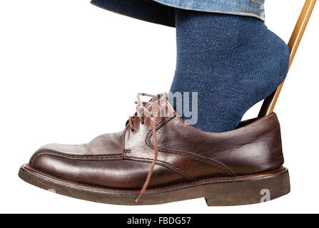 Man setzt auf braune Schuhe mit Schuhlöffel isoliert auf weißem Hintergrund Stockfoto