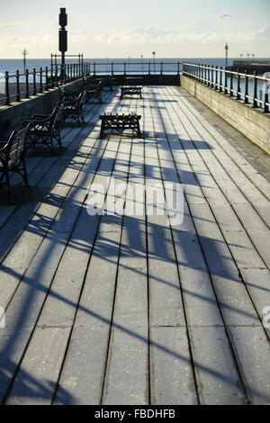 Lange Schatten auf den Frost bedeckt Holzterrassen von Littlehampton Pier in Littlehampton, West Sussex, England. Stockfoto