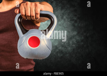 Zusammengesetztes Bild des Innenfeldes ein muskulöser Mann hält eine kettlebell Stockfoto