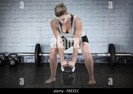 Zusammengesetztes Bild von Ernst muskulöse Frau Kettlebell lifting Stockfoto