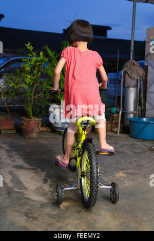 Glückliches Mädchen auf ihr Kind Fahrrad fahren lernen unterstützen Räder. Stockfoto