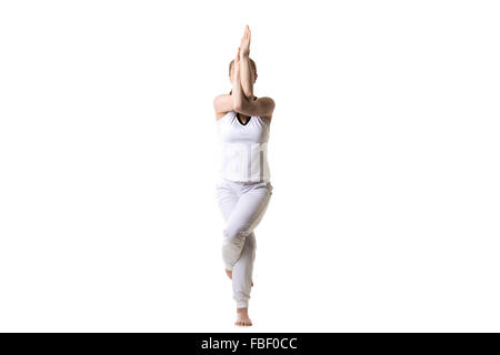 Schöne Fitness-Modell praktiziert Yoga oder Pilates, stehend im Yoga Adler Pose, Garudasana, Vorderansicht, Studio gedreht, isoliert Stockfoto