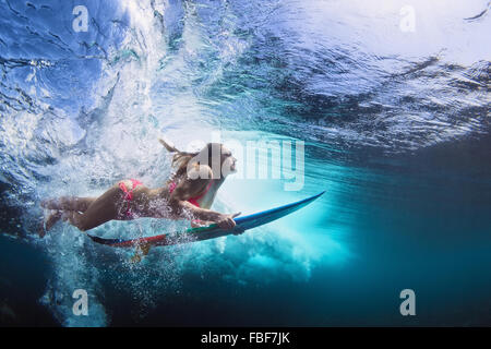 Junges Mädchen im Bikini - Surfer mit Surf Board Tauchgang unter Wasser mit Spaß unter großen Ozeanwelle.