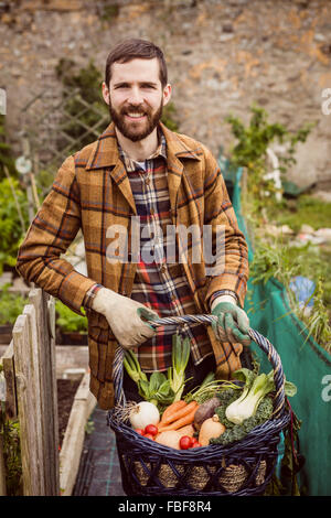 Lächelnder Mann hält Korb mit Gemüse Stockfoto