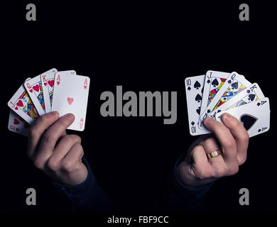 Kaukasische männliche Hände halten zwei Royal Flush Poker-Kombination aus Herz und Pik. Low-Key Lichtkomposition Stockfoto