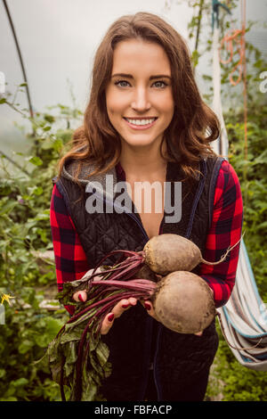 Lächelnde Frau hält und zeigt rote Beete Stockfoto