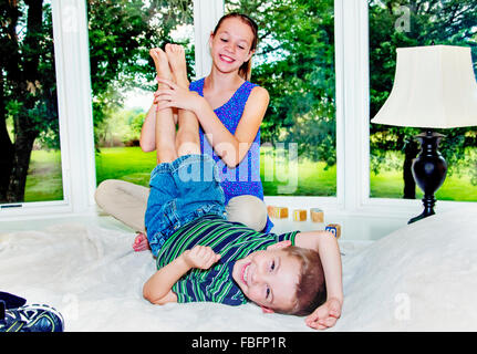 Mädchen Jungen Füßchen auf Bett kitzeln Stockfoto