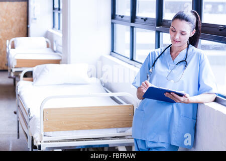 Ernsthafte Krankenschwester hält Bericht über die Zwischenablage Stockfoto