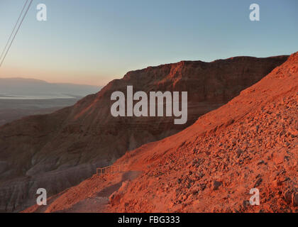 Wandern Masada in Israel bei Sonnenaufgang mit dem Sonnenlicht wirft eine rote anschlagen die Sandsteinfelsen Stockfoto