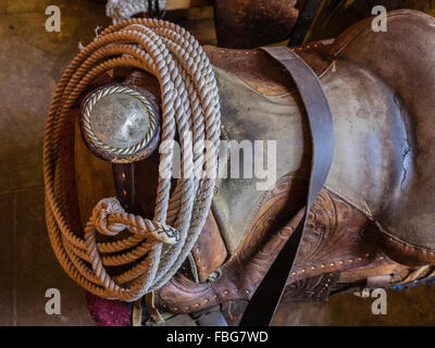 Eine Nahaufnahme von einer silbernen gravierte Antik Sattel-Horn und ein Lasso aufgerollt in einer Scheune mit Fensterlicht um ihn herum. Stockfoto