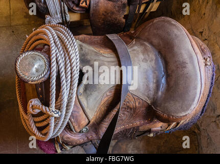 Eine Nahaufnahme von einer silbernen gravierte Antik Sattel-Horn und ein Lasso aufgerollt in einer Scheune mit Fensterlicht um ihn herum. Stockfoto