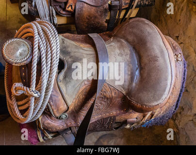 Eine Nahaufnahme von einer silbernen gravierte Antik Sattel-Horn und ein Lasso aufgerollt in einer Scheune mit Fensterlicht um ihn herum. Stockfoto