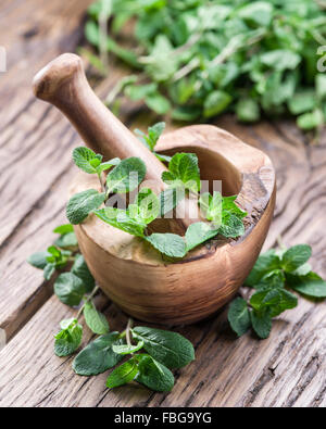 Frische Minze, hölzerne Mörser und Stößel auf dem alten Tisch. Stockfoto