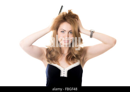 Lustige Porträt junge attraktive fröhlich lächelnden blonden Frau mit langen Haaren halten Kamm, Blick in die Kamera wie in Spiegel, versuchen Stockfoto