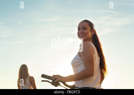 Zwei Teenager Biker Girls fahren auf sonnigen Sommertag, Fokus auf Brünette sportlich schöne junge Frau mit Motorrad Rückblick auf ca Stockfoto