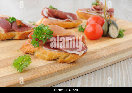 Brotscheiben mit spanischen Jamon Serrano auf einem Holzbrett Stockfoto