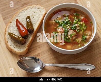 Essen - Suppe mit Frikadellen mit Chili Peppers und Brot - Holz-Hintergrund Stockfoto