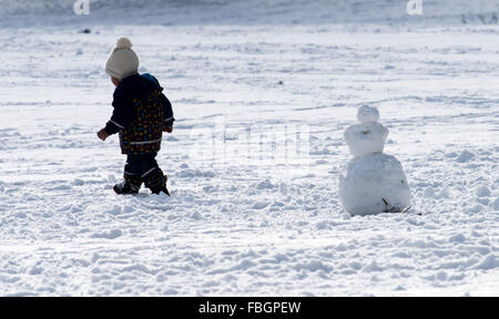 München, Deutschland. 16. Januar 2016. Ein Kind baut einen kleinen Schneemann im englischen Garten in München, Deutschland, 16. Januar 2016. Foto: PETER KNEFFEL/Dpa/Alamy Live News Stockfoto