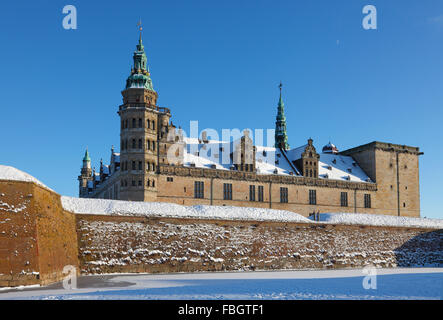 Die verschneite Schloss Kronborg in Helsingør, Helsingör, an einem sonnigen Wintertag, gefroren Wassergraben und einem blauen Himmel. Stockfoto