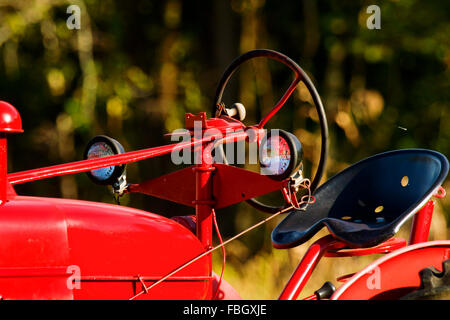 Eine alte rote Traktor mit Fokus auf die Lichter, Lenkrad und Sitz. Stockfoto