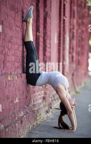 Yoga in der Stadt: schöne sportliche junge Frau arbeiten auf der Straße neben alten roten Backsteinmauer, Handstand, Variation o zu tun Stockfoto