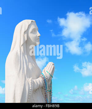 Heilige Jungfrau Maria Statue beten unter blauem Himmel Stockfoto