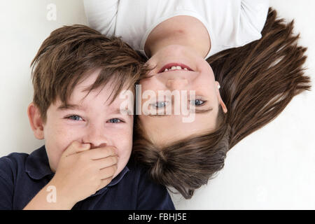 Freche Kinder lustige Grimassen einander an, während auf dem Boden verlegen Stockfoto