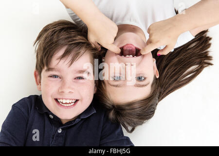 Freche Kinder lustige Grimassen einander an, während auf dem Boden verlegen Stockfoto