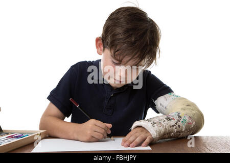 kleiner Junge, ein Bild zu zeichnen, während er einen gebrochenen linken Arm hat Stockfoto