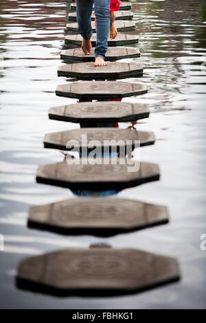 Besucher, die auf steinernen Spuren im Tirta Gangga Wasserpalast in Karangasem, Bali, Indonesien, spazieren. Stockfoto